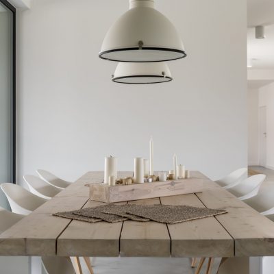 Room with wood dining table, white chairs and industrial lamp