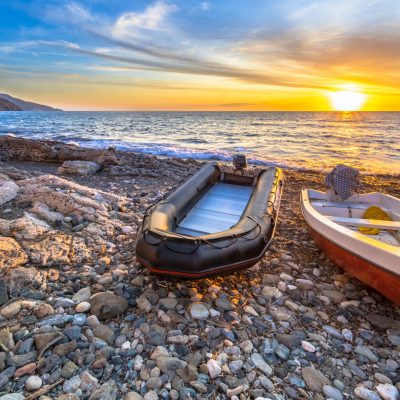 Two boats at sunset on a pebble beach on Cap Corse, Corsica, France.