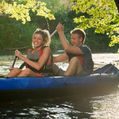 Smiling couple kayaking in creek