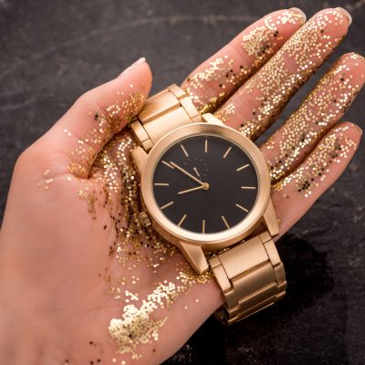cropped view of golden wristwatch in hand of woman