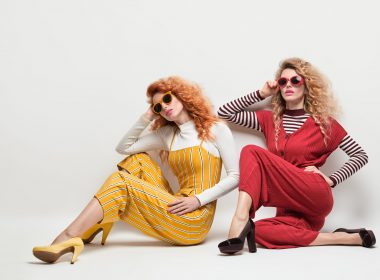 Fashion. Gorgeous Woman in Red Yellow jumpsuit, Sunglasses, heels. Creative Elegant Style. Two Sexy Girl in Trendy Outfit with Curly Hairstyle. Young Playful Sisters Friends. Creative Vintage