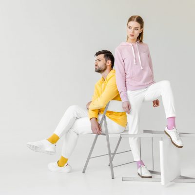 young male and female models in pink and yellow hoodies on white